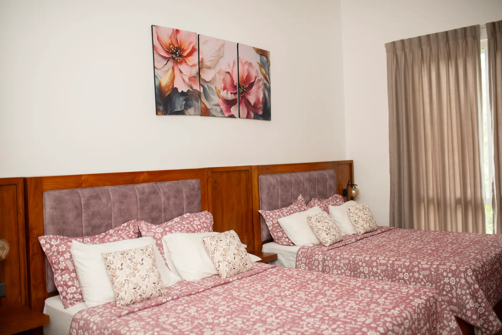 Twin beds with pink floral bedding, mauve headboards, and floral wall art