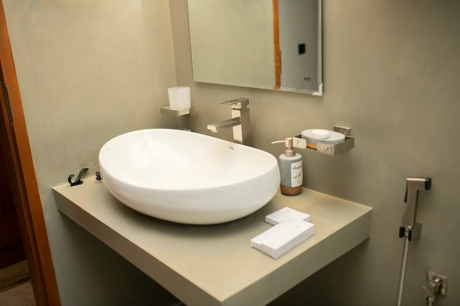 Ensuite vanity with a white vessel sink, wall-mounted faucet, and grey stone counter