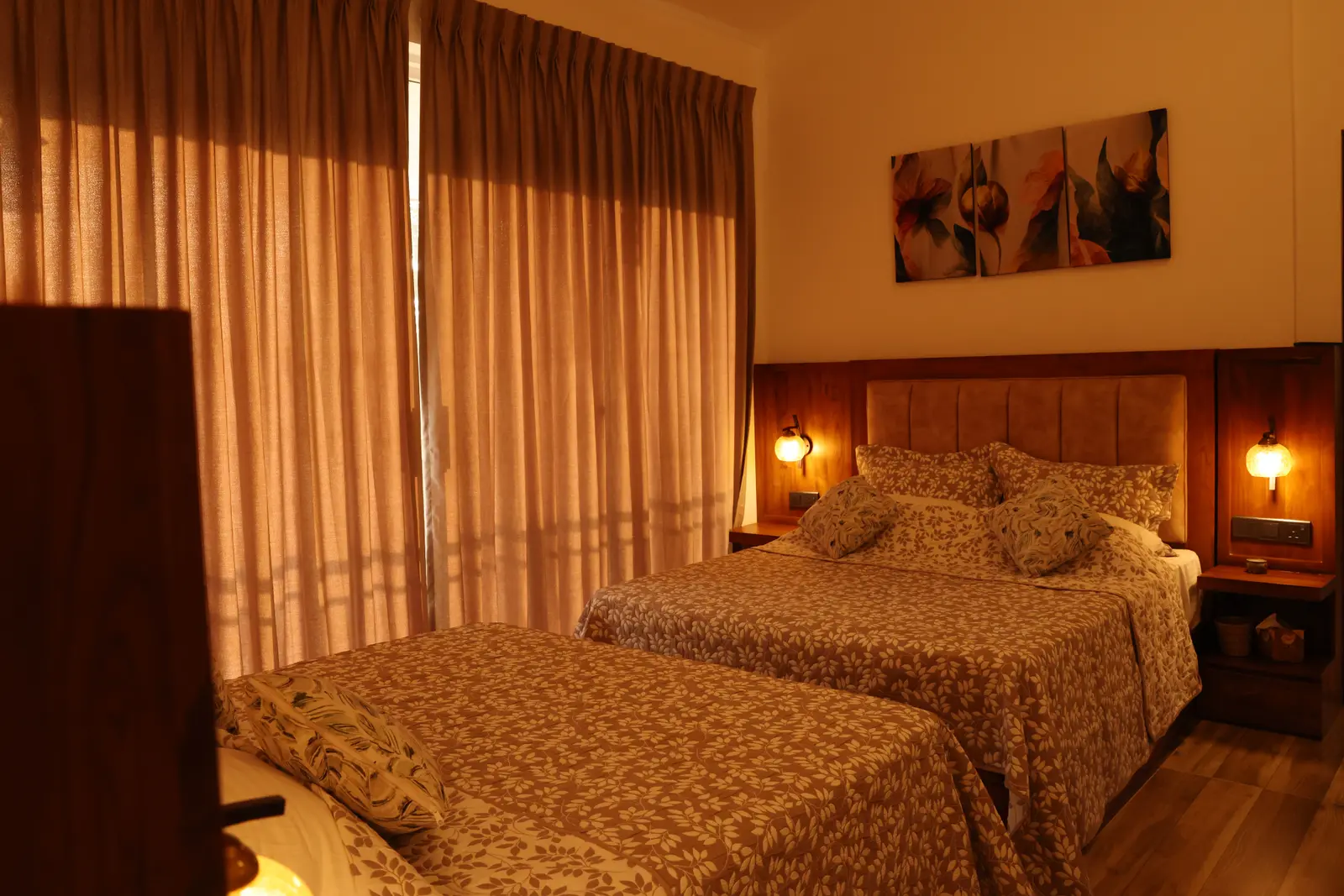 Twin beds with amber bedside lamps and floral wall art