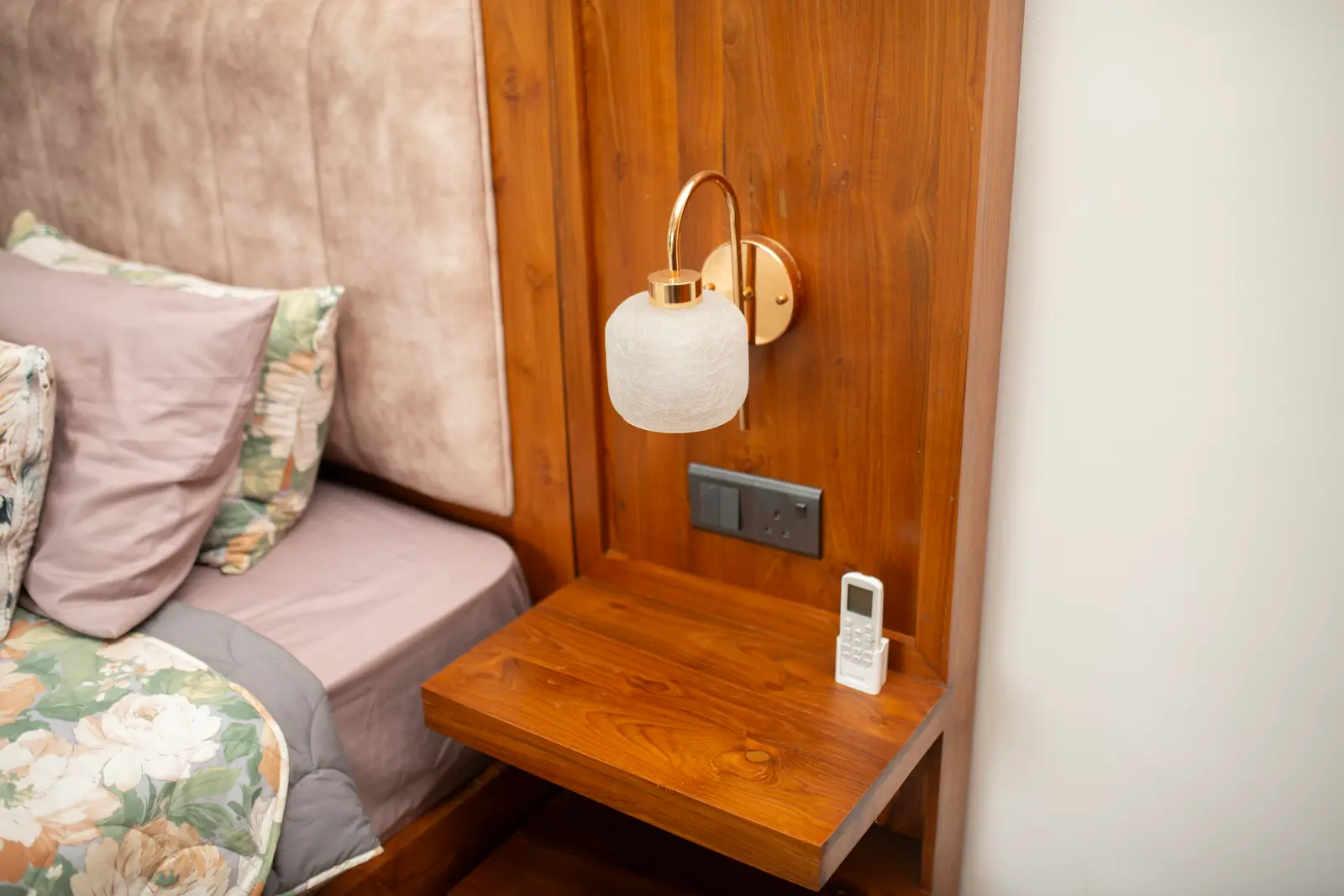 Floating nightstand with globe lamp beside floral bedding