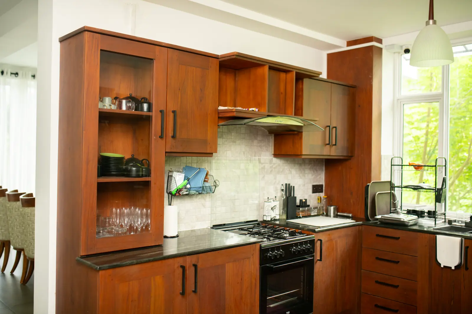 Chef's kitchen with wooden cabinetry, black stone counters, and forest views