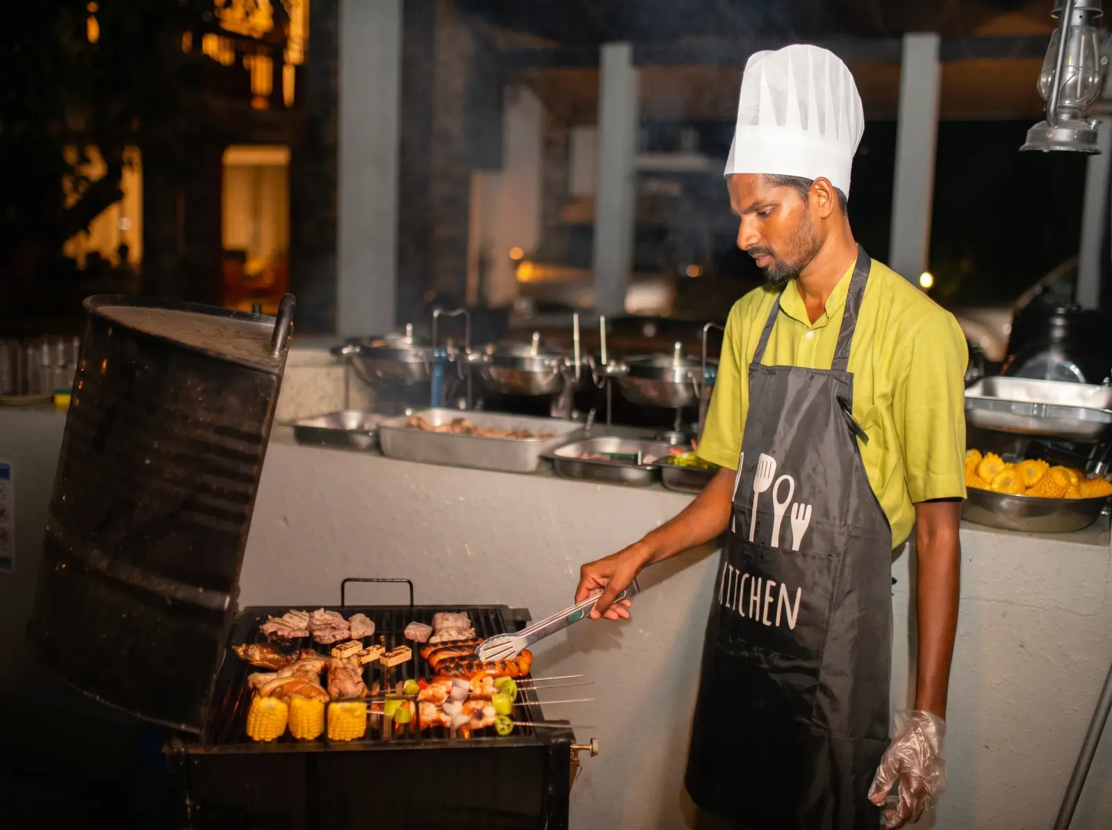 Private chef grilling skewers and corn over an outdoor barbecue